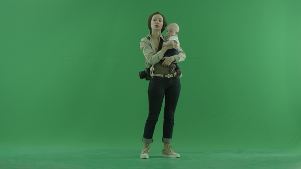 A Young Woman Is Talking with Her Baby on the Green Screen