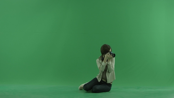 Sitting Young Woman Is Taking Photos Around Her on the Green Screen