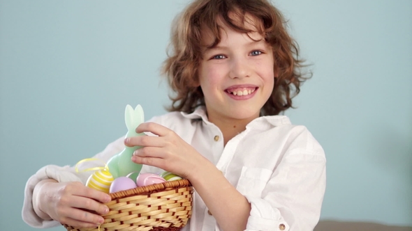 A Child Holds a Easter Bunny and a Set of Decorative Easter Eggs. The Boy Laughs Cheerfully. alt