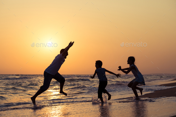 Father son and daughter playing on the beach at the sunset time. - Stock Photo - Images