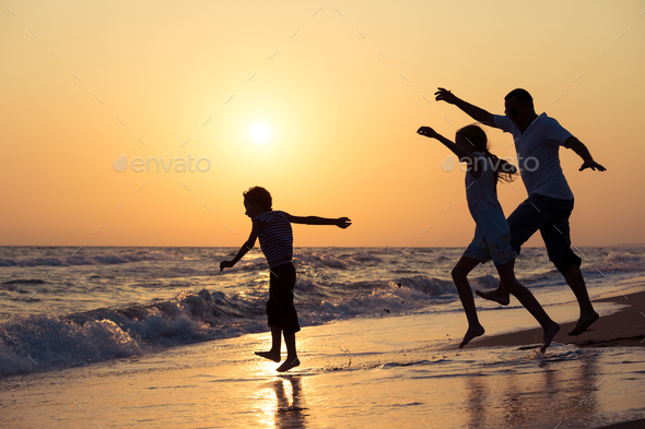 Father son and daughter playing on the beach at the sunset time. - Stock Photo - Images