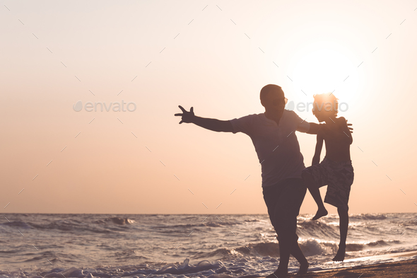 Father and son playing on the beach at the sunset time. - Stock Photo - Images