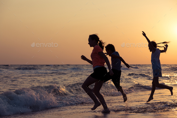 Happy children playing on the beach at the sunset time. - Stock Photo - Images