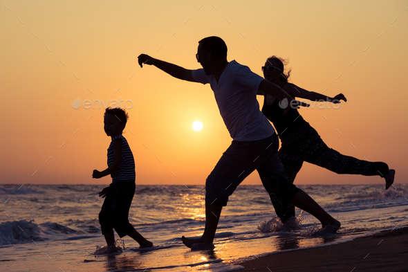 Father mother and son playing on the beach at the sunset time. - Stock Photo - Images