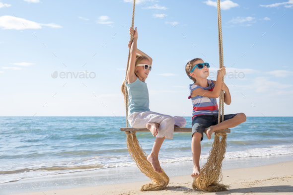 Two happy little children playing on the beach at the day time. - Stock Photo - Images