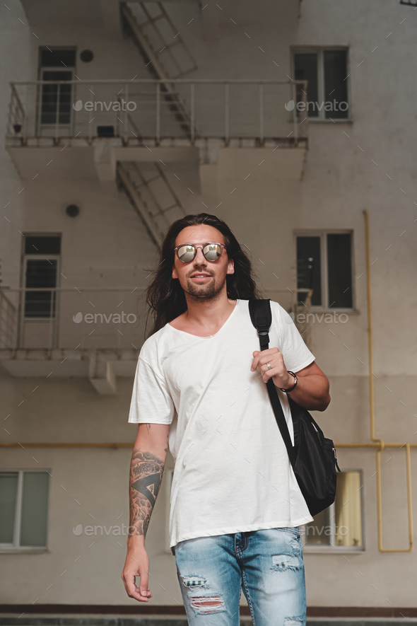 Man on urban background with backpack and sunglasses - Stock Photo - Images