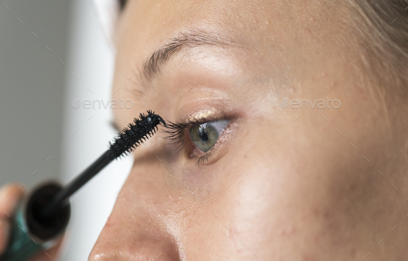 Portrait of white woman doing her daily makeup routine - Stock Photo - Images