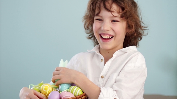 Portrait of a Curly Red-haired Boy with a Basket of Easter Eggs in his Hands alt
