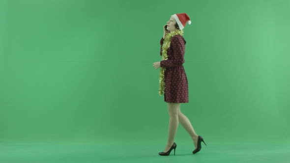 A Young Christmas Woman Is Going From the Right Side and Talking on Her Phone on the Green Screen
