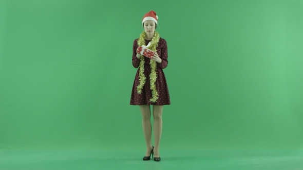 A Young Woman Is Looking for a Christmas Gift and Shaking It on the Green Screen