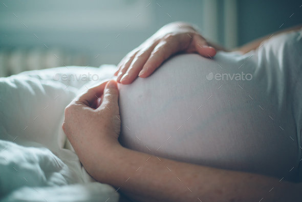 Sweet photo focus on the belly of pregnant lady cuddling her belly
