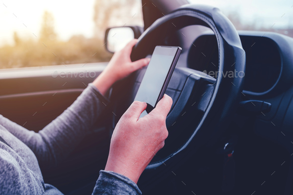 Woman simultaneously driving car and reading text message - Stock Photo - Images