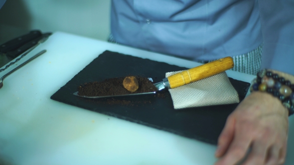 the Chef Puts the Truffle on a Spatula with Chocolate Powder