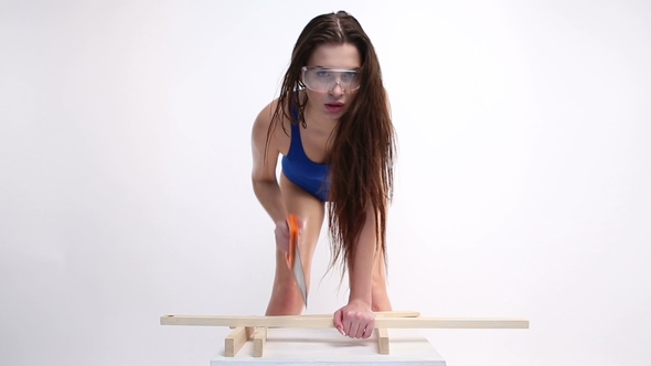 Sexy Woman in a Blue Swimsuit Sawing Wooden Beams with Saw. the Beautiful Girl Moves