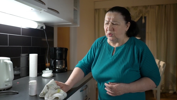 Senior Woman Suffering From Stomach Ache at Home and Takes the Pills alt