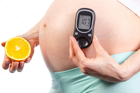 Pregnant woman holding glucose meter with sugar level and orange, diabetes during pregnancy - Stock Photo - Images