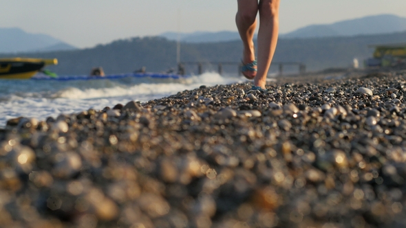 Shot of Slim Woman's Legs Moving To Camera, Pebble Coast and Panorama of Mountains