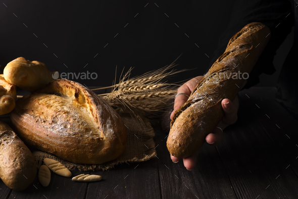 Baker woman holding rustic organic loaf of bread in hands - rural baker - Stock Photo - Images