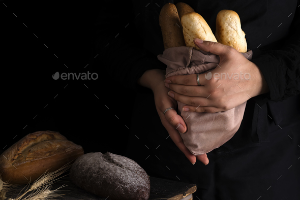 Baker woman holding rustic organic loaf of bread in hands - rural baker Stock Photo by lyulkamazur