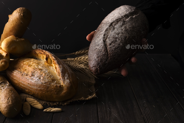 Baker woman holding rustic organic loaf of bread in hands - rural baker - Stock Photo - Images
