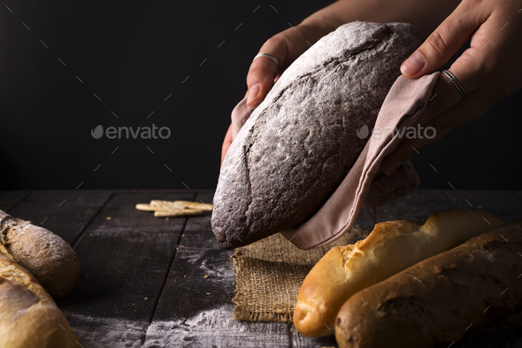 Baker woman holding rustic organic loaf of bread in hands - rural baker - Stock Photo - Images