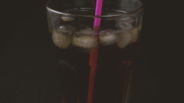 Female Hand Stirs Cold Tea with a Cocktail Straw