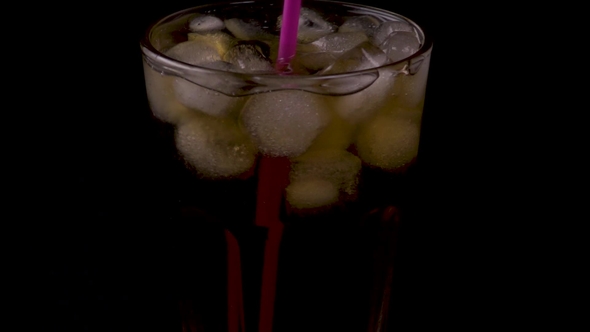 Woman Stirs a Cold Drink with a Cocktail Straw on a Black Background