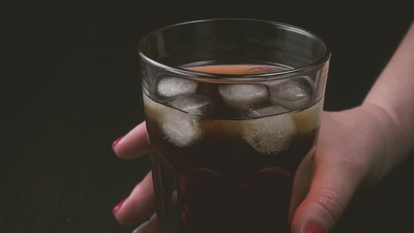 Woman's Hand Takes a Glass of Cold Tea From the Table