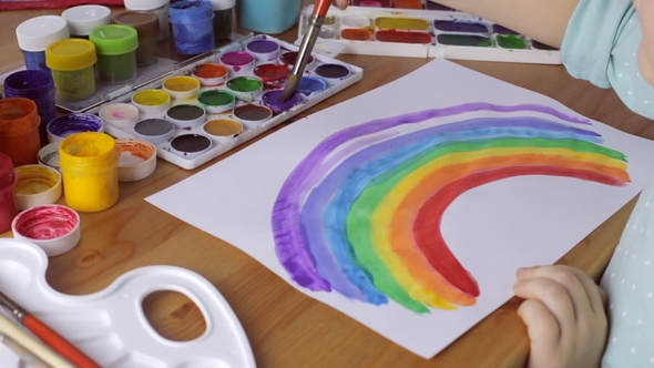 Young Girl Painting a Colored Rainbow on White Paper