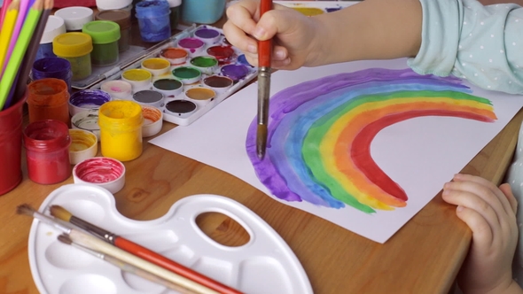 Young Girl Drawing Colored Rainbow at Home