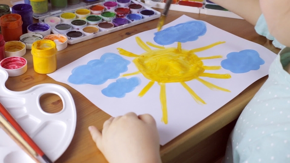 Cute Young Girl Draws Yellow Sun and Blue Clouds. Painting Concept