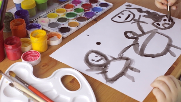 Sad Young Girl Draws People with Black Paints on White Paper