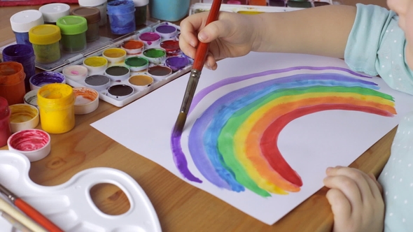 Cute Young Girl Draws Colored Rainbow on White Paper