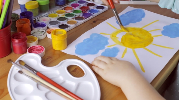 Young Girl Painting a Yellow Sun on White Paper