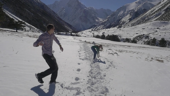 Couple of Young People Playing Snowball in the Mountains