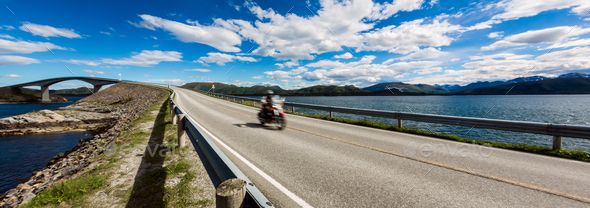 Biker rides a road with Atlantic Ocean Road in Norway. - Stock Photo - Images