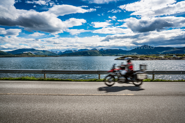 Biker rides a road with Atlantic Ocean Road in Norway. - Stock Photo - Images