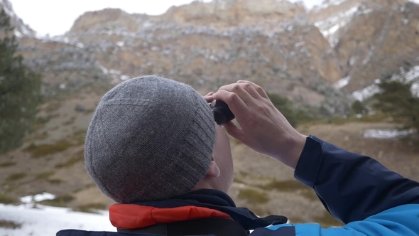 Man Looks Through Binoculars in the Mountains