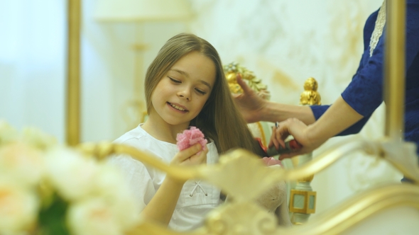 Charming Little Girl Is Smiling While Her Beautiful Young Mother Is Combing Daughter's Hair