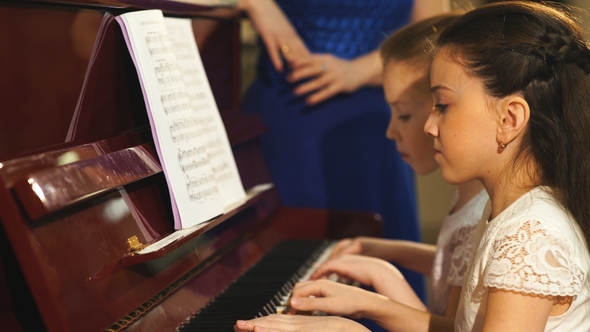 Family, Mother and Daughters Learn To Play Piano Together in Home