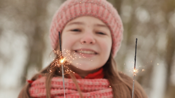 A Happy Young Schoolgirl with Sparkling Sparks of Bengal Lights Among the Winter Forest alt