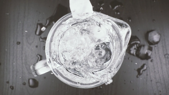 Ice Cubes Fall Into a Carafe with Water