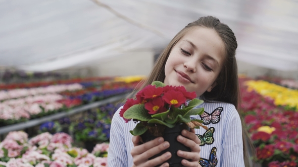 Happy Girl Choosing and Smelling Flower Seedling alt