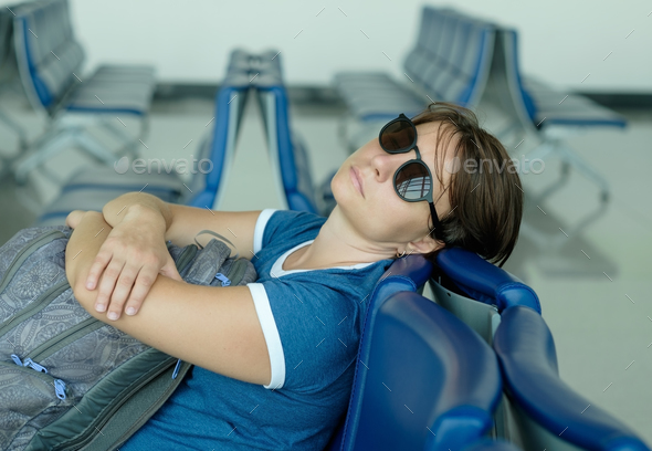Tired caucasian woman sleeping in airport lounge waiting for flight - Stock Photo - Images