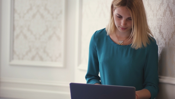 Young Woman Opening Laptop Computer for Browsing Internet in Room Interior alt