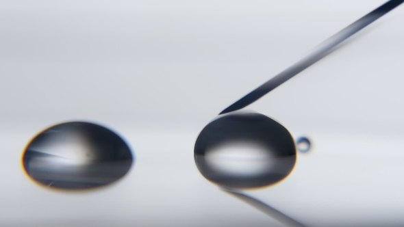 Transparent Water Drop Is Absorbed By a Metallic Needle in a Scientific Lab