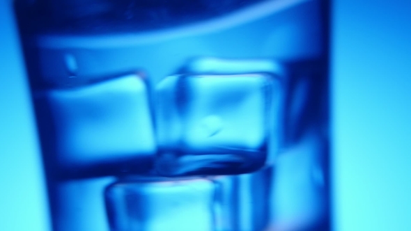 Several Ice Cubes Are Shaken in a Crystal-clear Glass in the Blue Background