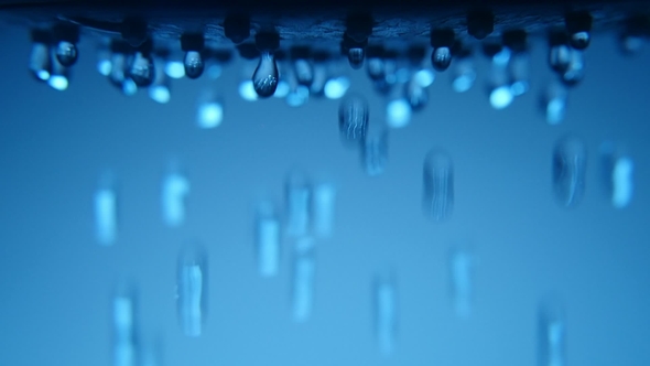 Dozens of Luminous Blobs Fall From a Shower Nozzle in a Blue Bathroom