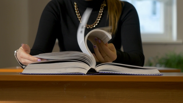 Women's Hands Leafing Through a Book. Woman Sitting at the Table Leafing Through the Book alt