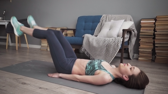 Fitness Woman Doing Leg Raise Exercise for Core Muscles at Home